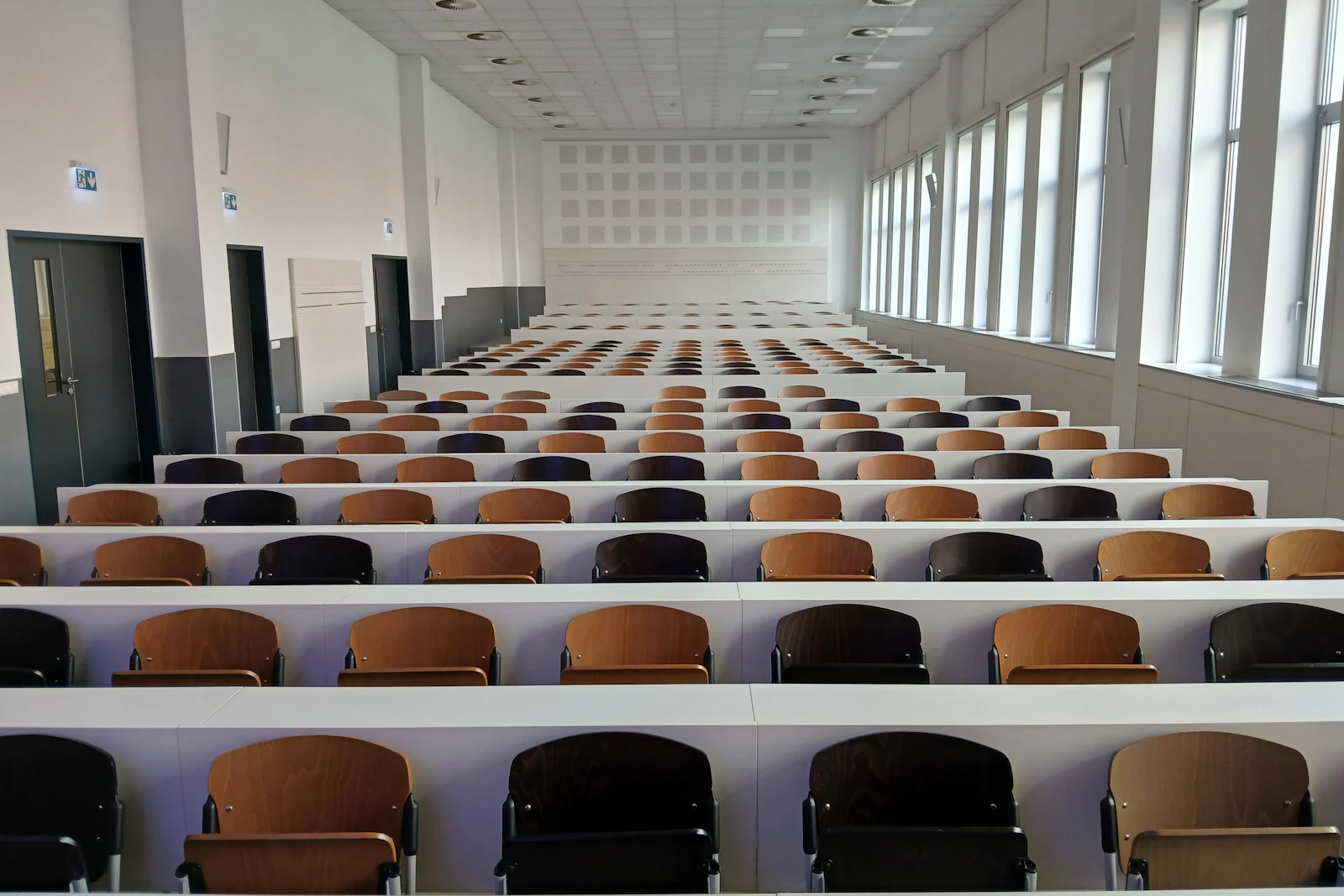 Leerer Hörsaal mit langen Sitzreihen aus Holz und Klappsitzen – 1. Semester Zahnmedizin