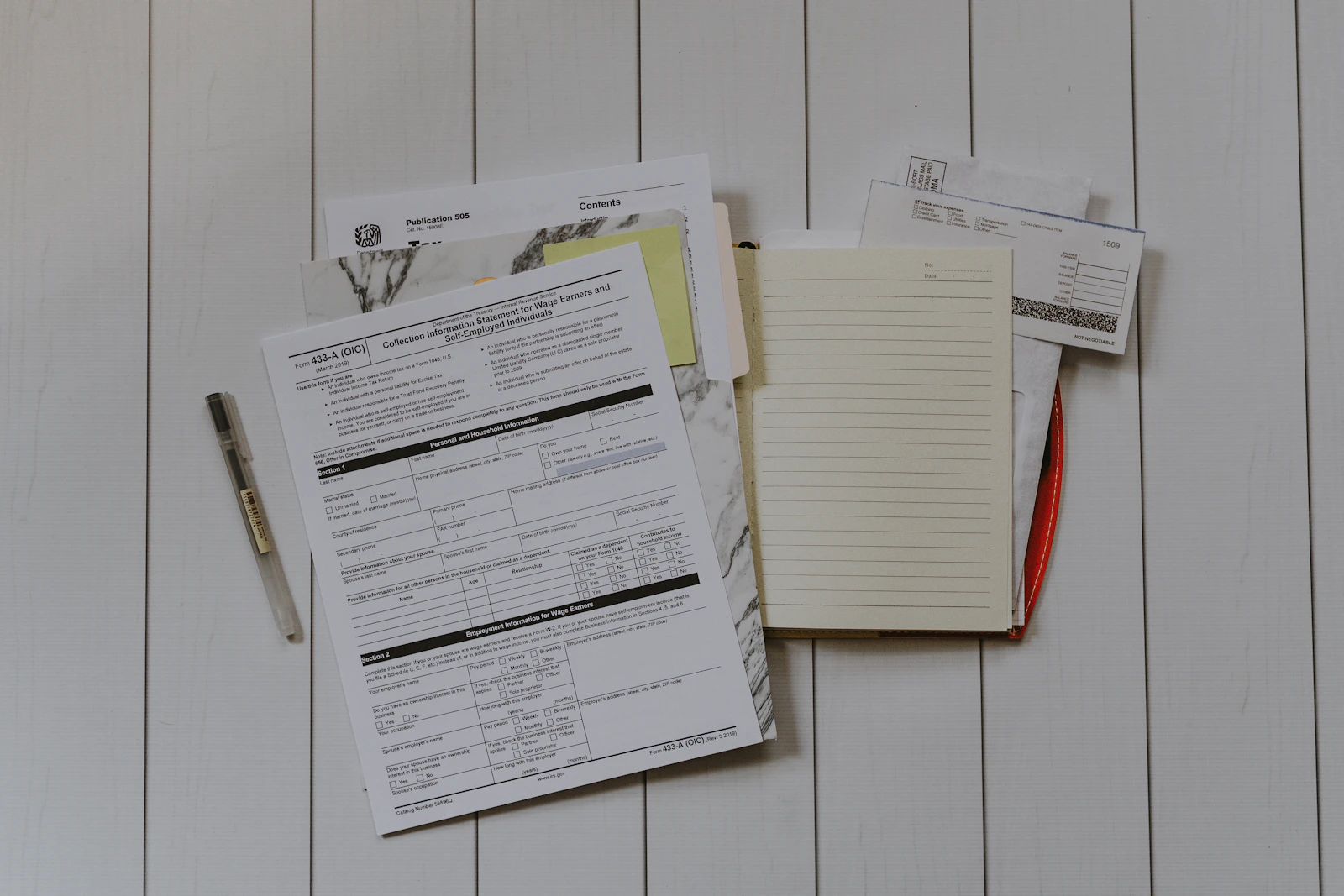 Formulare, Notizblock und Stift auf hellem Holztisch – Arbeitsvertrag Assistenzzahnarzt prüfen