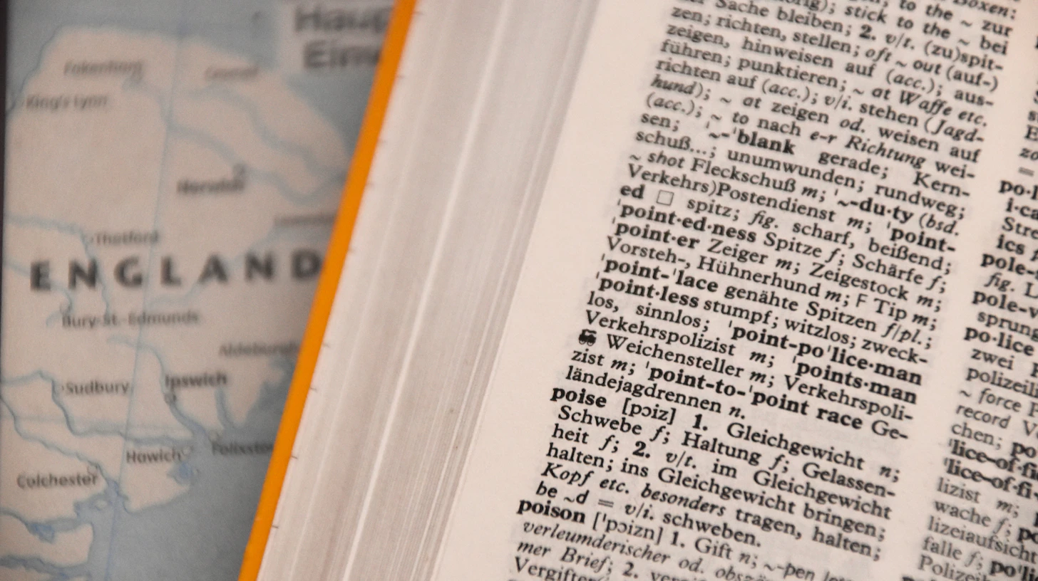 Aufgeschlagenes Wörterbuch mit Fachbegriffen neben einer Landkarte – Fachsprachprüfung Zahnmedizin