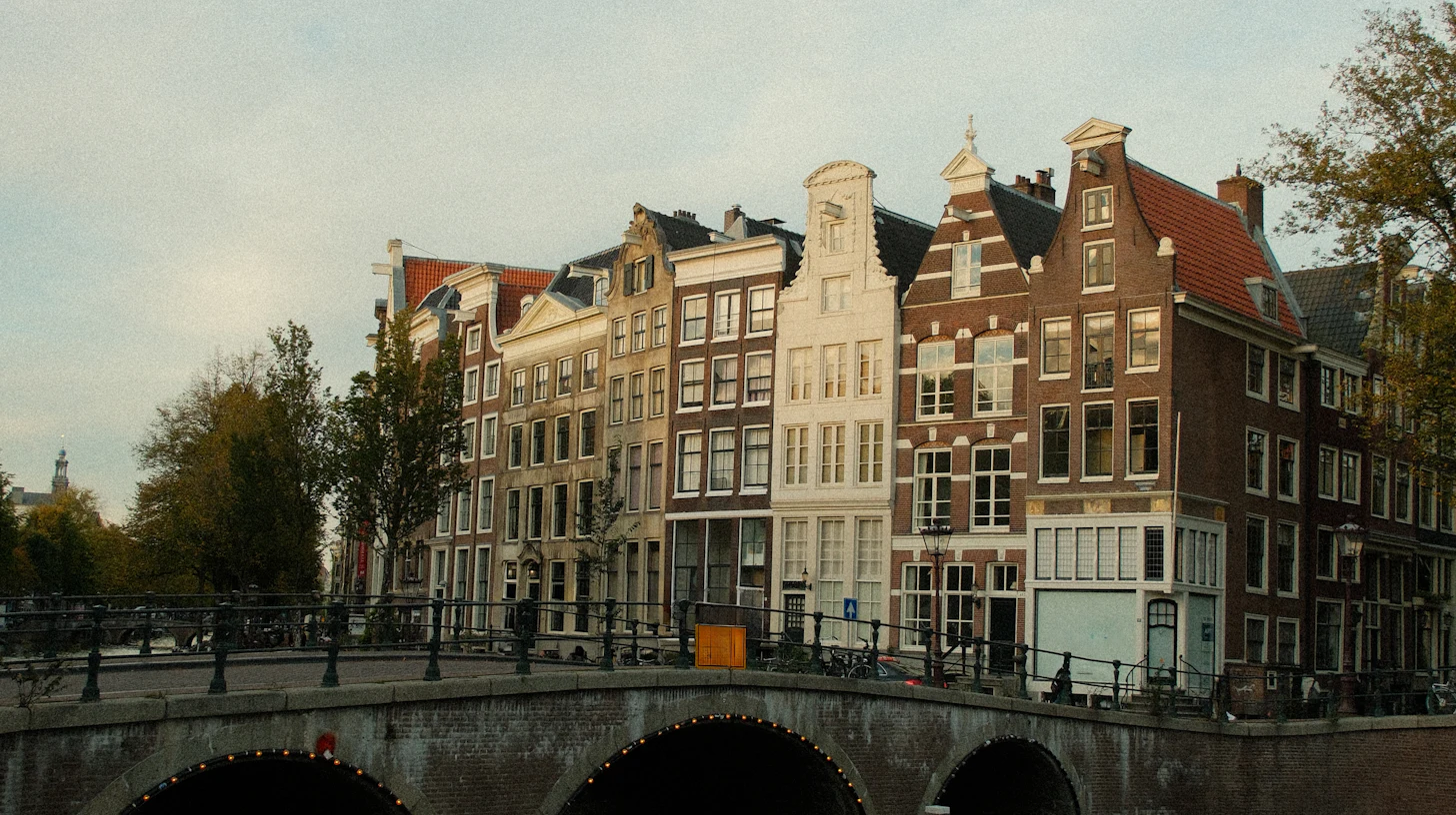 Grachtenhäuser mit Giebeln neben einer Steinbrücke in Amsterdam – Zahnmedizinstudium in den Niederlanden